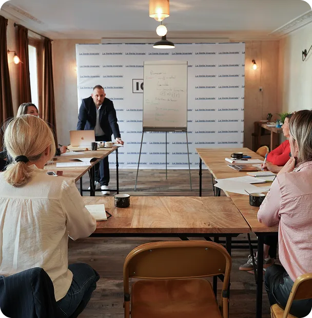 Julien anime une session au tableau devant un groupe de participants